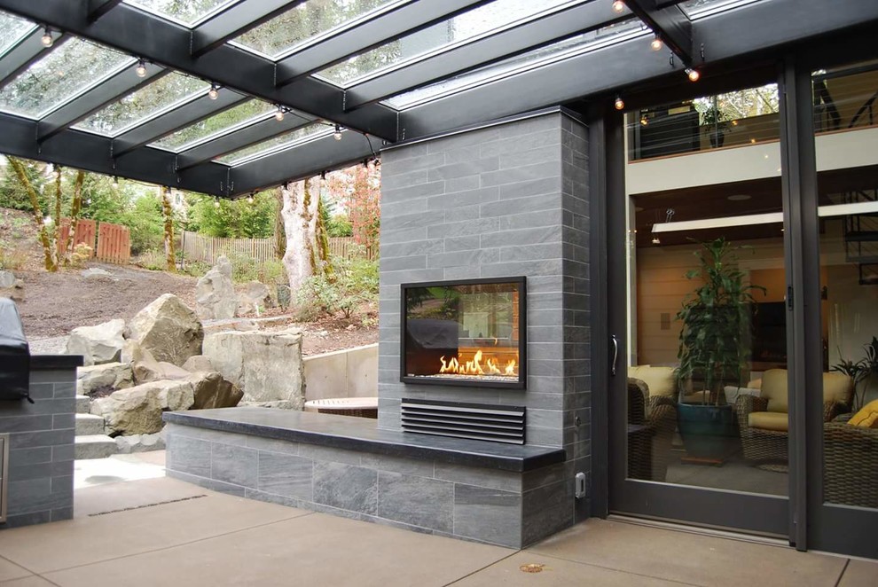 Esempio di un patio o portico design di medie dimensioni e dietro casa con un focolare, lastre di cemento e una pergola