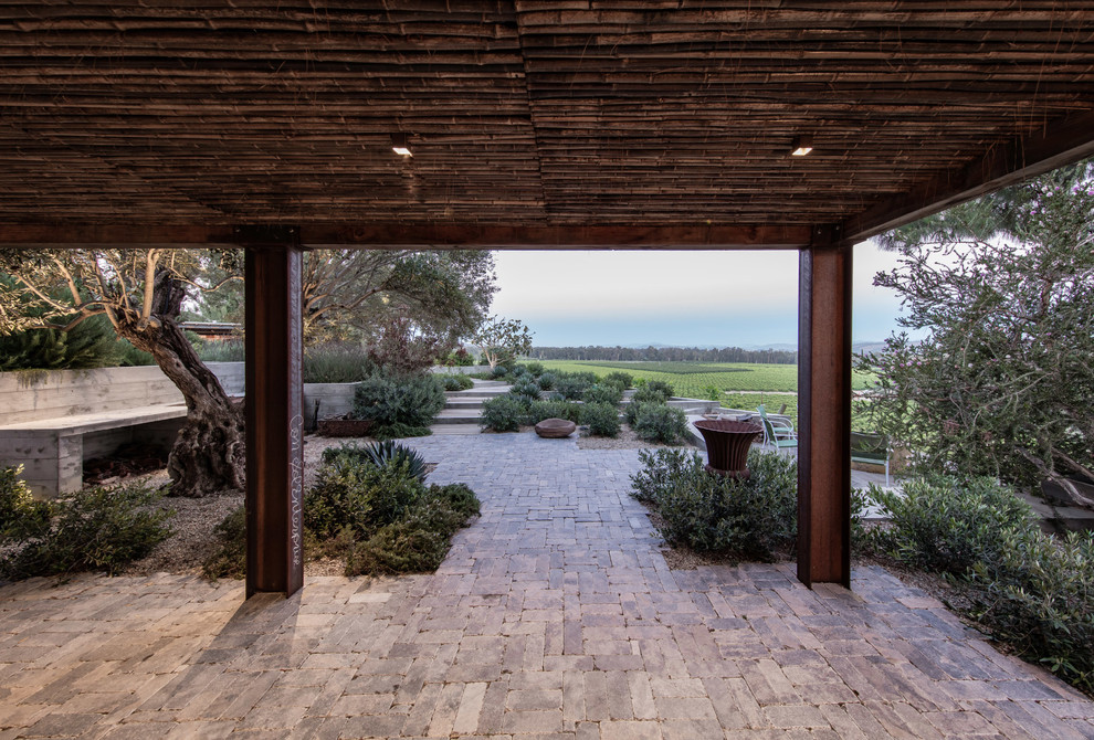 Example of a trendy backyard stone patio design in Santa Barbara with a roof extension