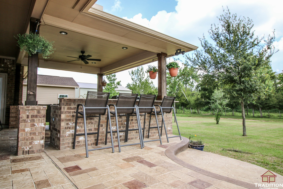 Immagine di un grande patio o portico chic dietro casa con cemento stampato e un tetto a sbalzo