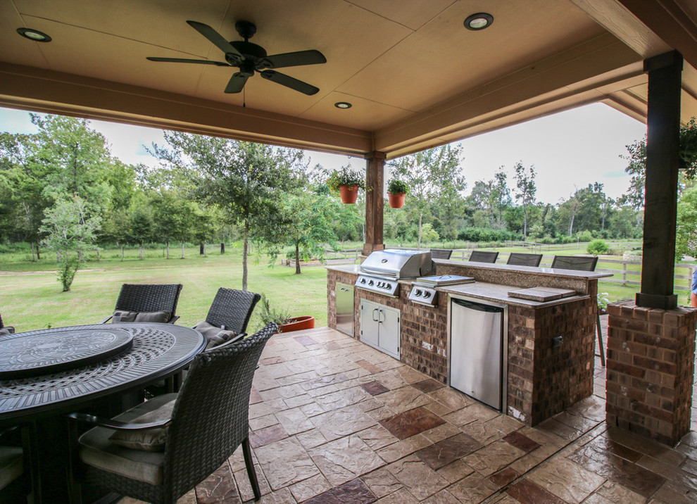 Large classic back patio in Houston with an outdoor kitchen, stamped concrete and a roof extension.