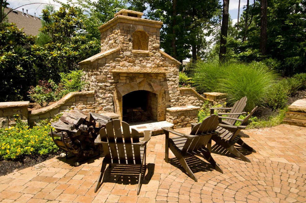 Immagine di un patio o portico chic con pavimentazioni in mattoni e un focolare