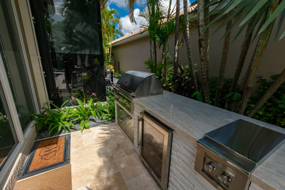 Design ideas for a contemporary back patio in Miami with an outdoor kitchen, natural stone paving and no cover.