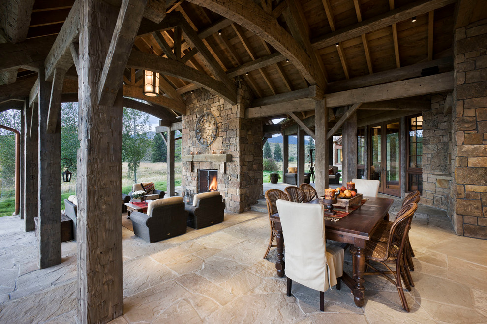 Mountain style stone patio photo in Other with a fire pit and a roof extension