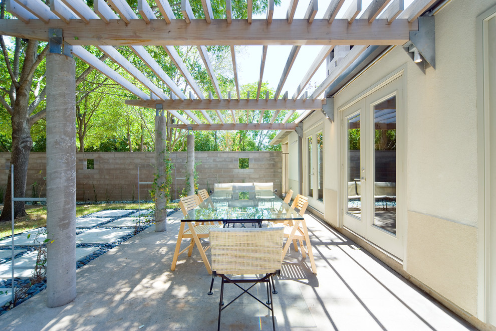 Diseño de patio contemporáneo con losas de hormigón y pérgola