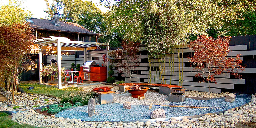 Foto de patio asiático de tamaño medio en patio trasero con brasero, gravilla y pérgola