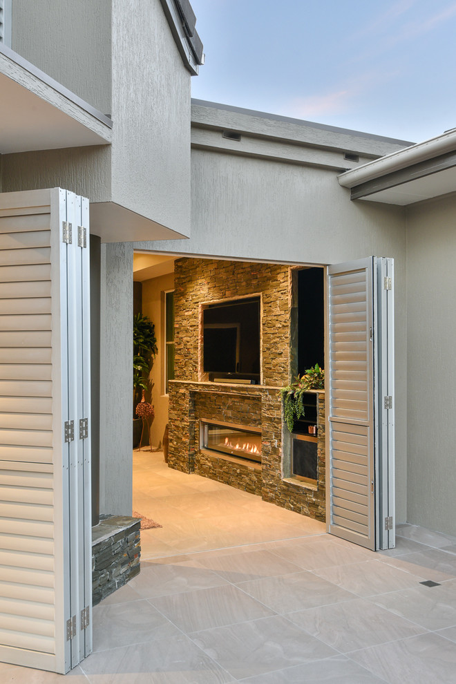 Inspiration pour une terrasse arrière design de taille moyenne avec un foyer extérieur, des pavés en pierre naturelle et une extension de toiture.