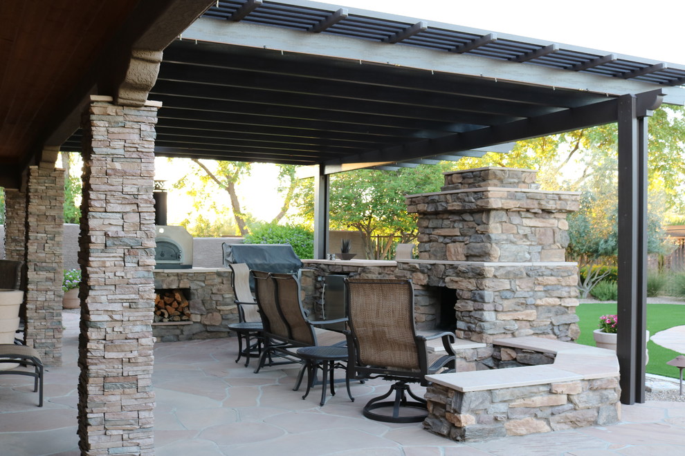 Mid-sized mountain style backyard stone patio kitchen photo in Phoenix with a pergola