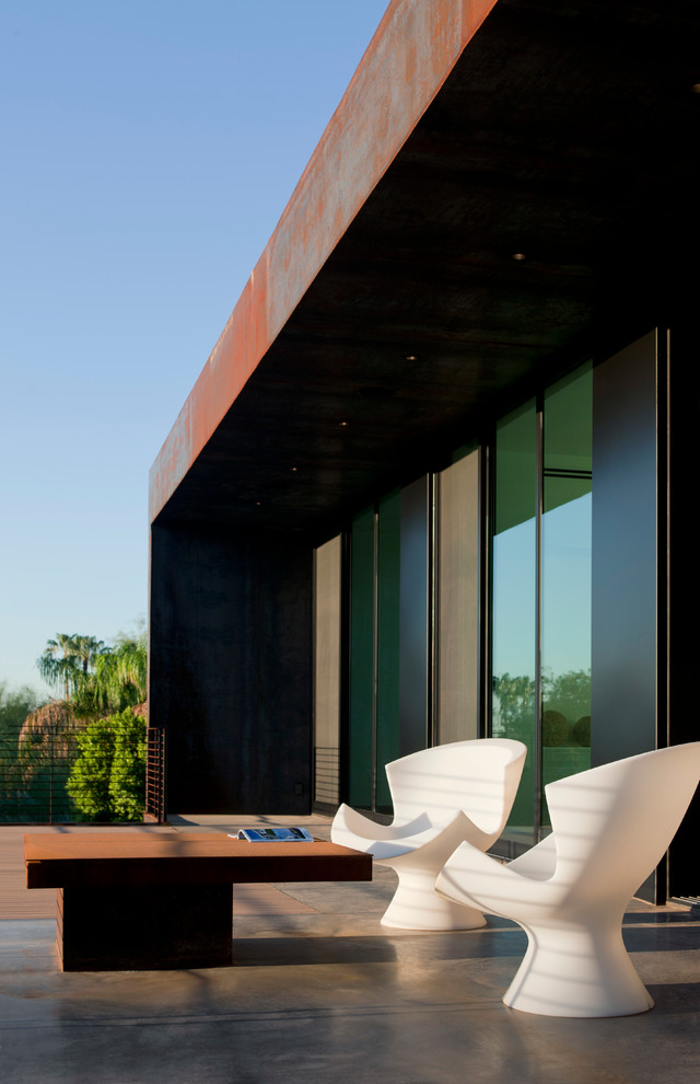 Inspiration for a medium sized modern front patio in Phoenix with a fire feature, concrete slabs and a roof extension.