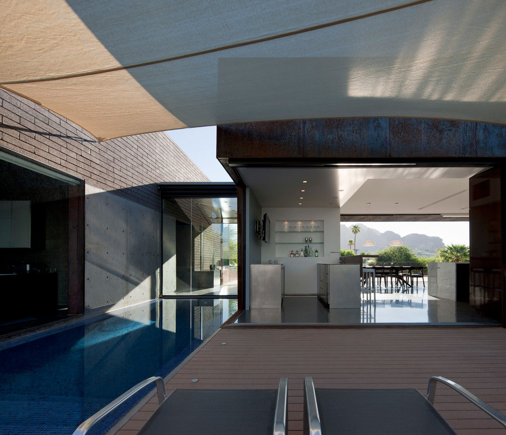 Inspiration pour une terrasse arrière minimaliste de taille moyenne avec une dalle de béton et un auvent.