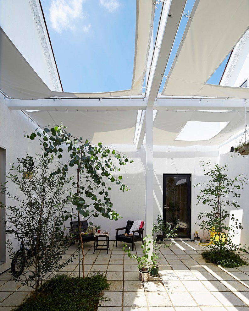 Cette photo montre une terrasse moderne de taille moyenne avec une cour, un auvent et des pavés en béton.