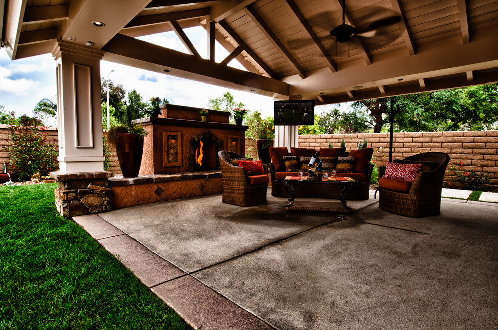 Foto de patio clásico renovado de tamaño medio en patio trasero y anexo de casas con chimenea y losas de hormigón