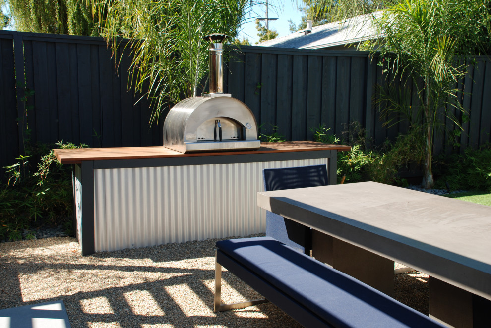 Réalisation d'une petite terrasse arrière design avec une cuisine d'été, du gravier et aucune couverture.