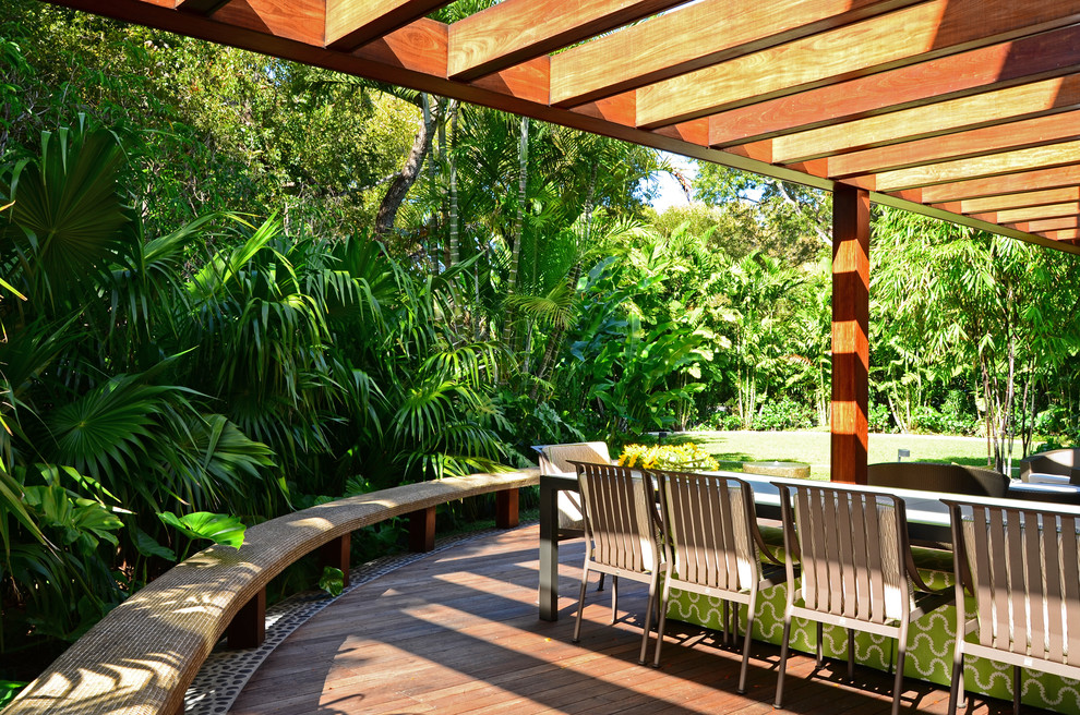 Diseño de patio tropical de tamaño medio en patio trasero con brasero, entablado y pérgola