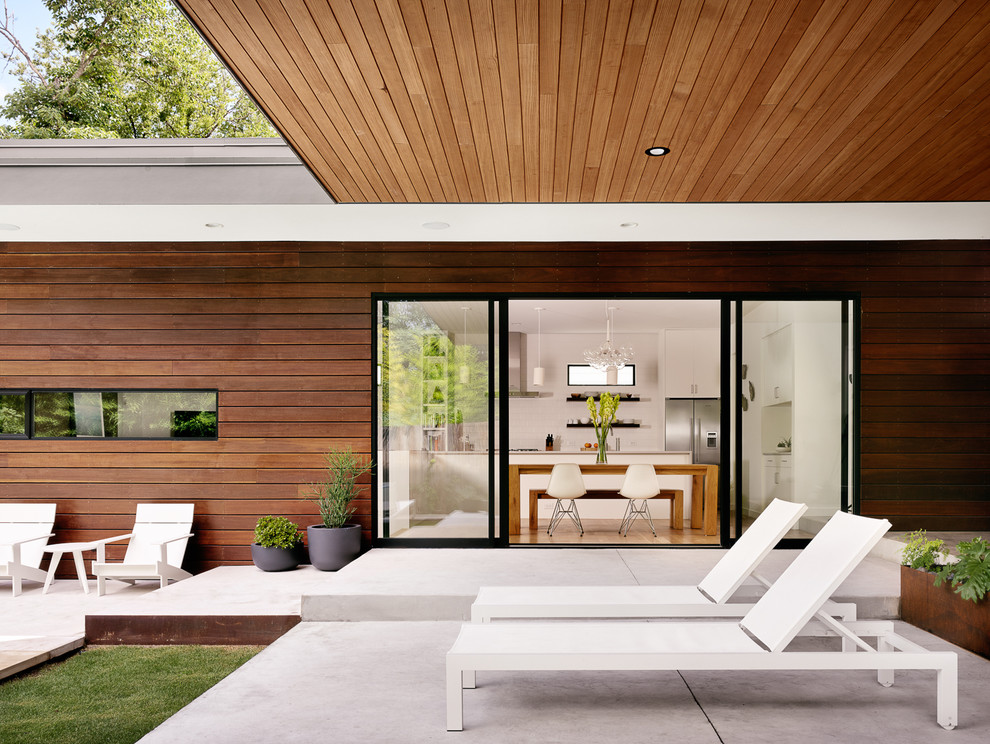 Cette photo montre une terrasse arrière tendance de taille moyenne avec des pavés en béton et une extension de toiture.