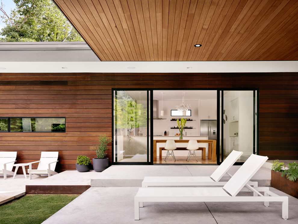 Idée de décoration pour une terrasse arrière design de taille moyenne avec une dalle de béton et une extension de toiture.