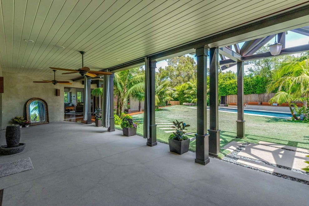 Foto di un patio o portico tropicale di medie dimensioni con pavimentazioni in cemento e un tetto a sbalzo