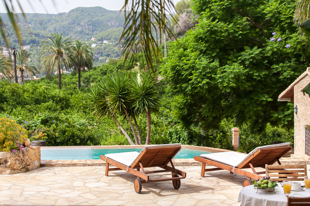 Diseño de piscina alargada mediterránea rectangular en patio trasero con adoquines de piedra natural