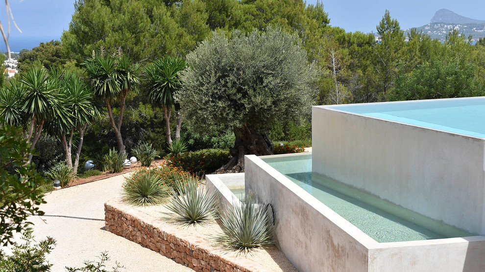 На фото: большой прямоугольный бассейн-инфинити на переднем дворе в средиземноморском стиле с покрытием из плитки