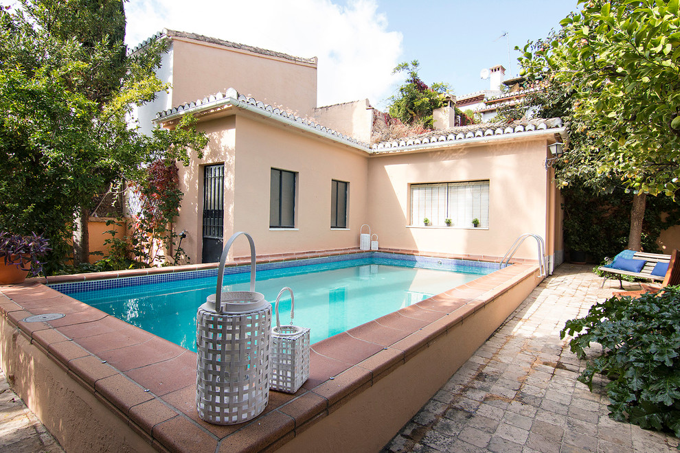 Diseño de piscina alargada mediterránea rectangular en patio trasero con adoquines de ladrillo