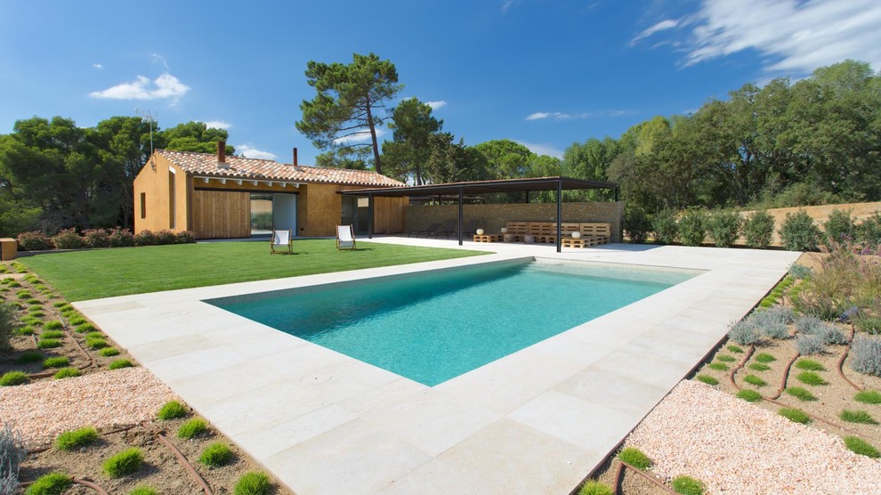 Imagen de casa de la piscina y piscina alargada campestre de tamaño medio rectangular en patio lateral con suelo de baldosas