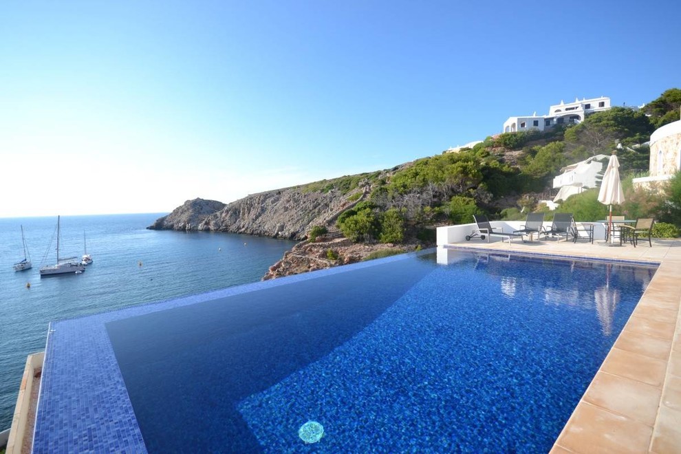 Immagine di una piscina a sfioro infinito mediterranea rettangolare di medie dimensioni e dietro casa con una dépendance a bordo piscina e piastrelle