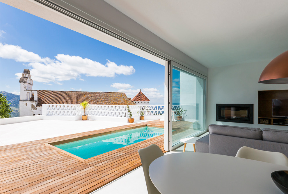 Ejemplo de casa de la piscina y piscina alargada mediterránea pequeña rectangular en patio lateral con entablado