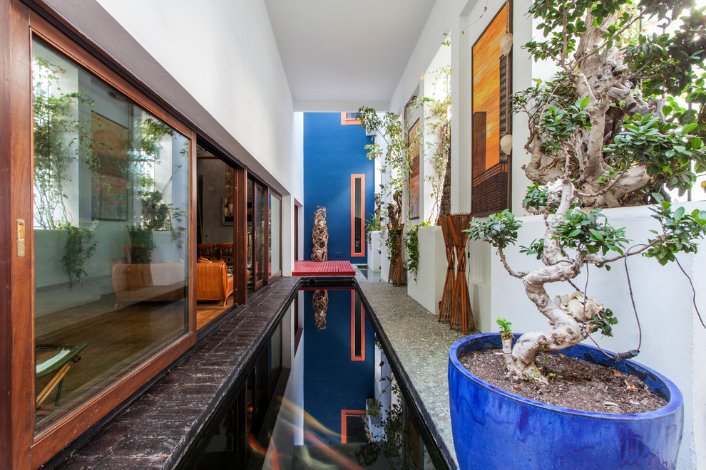 Esempio di una grande piscina monocorsia tropicale rettangolare in cortile con pavimentazioni in pietra naturale