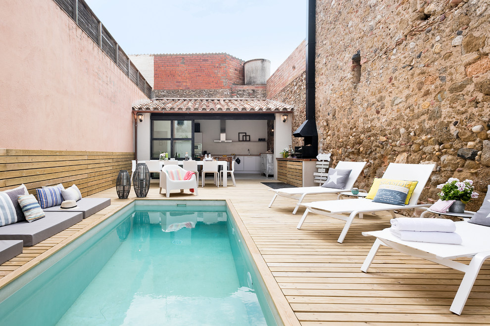 This is an example of a medium sized mediterranean back rectangular lengths swimming pool in Barcelona with a pool house and decking.