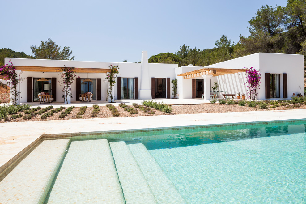 Foto de piscina alargada mediterránea de tamaño medio rectangular en patio trasero con gravilla