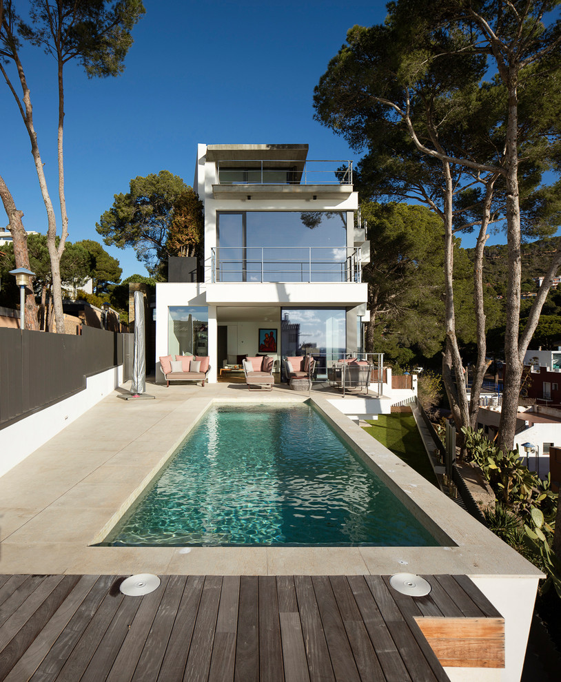 Photo of a medium sized contemporary back rectangular lengths swimming pool in Other with a pool house and tiled flooring.