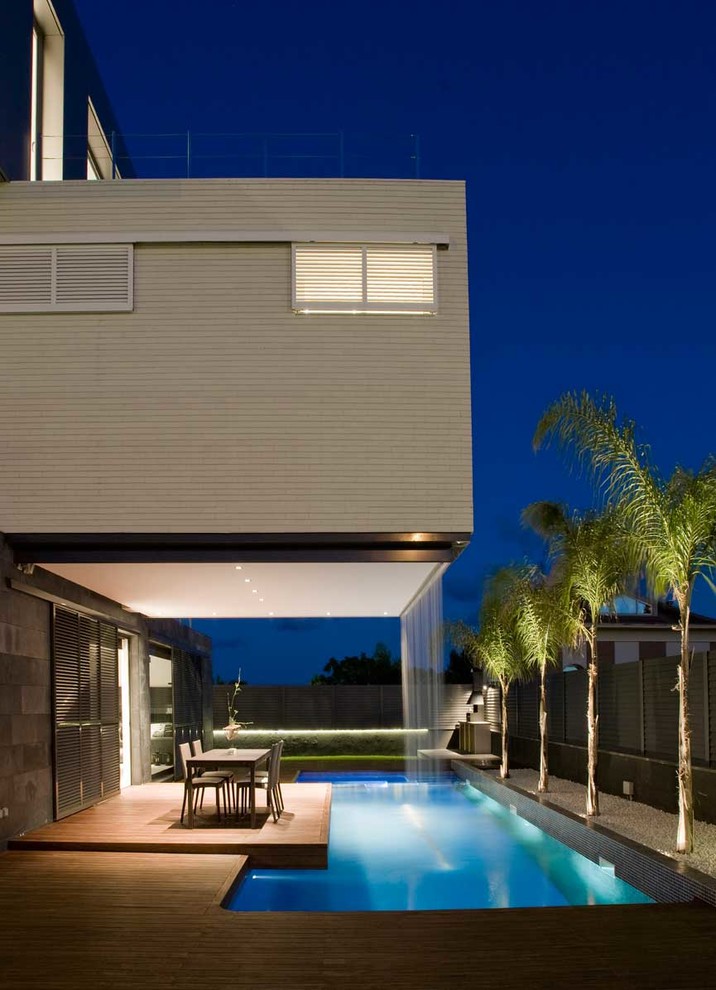 Imagen de casa de la piscina y piscina alargada actual pequeña rectangular en patio lateral con entablado