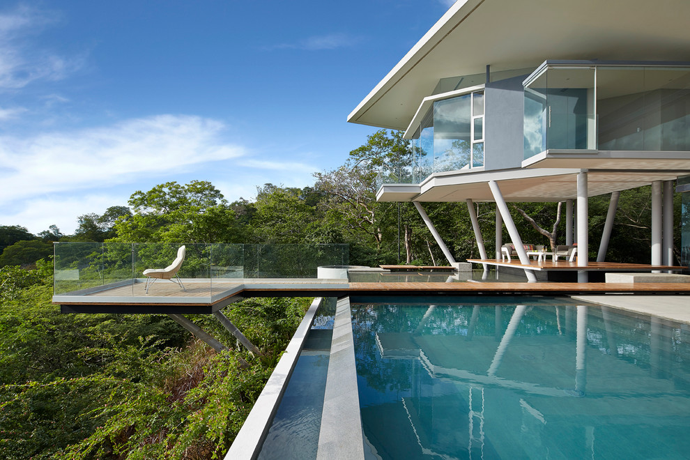 Exemple d'une piscine à débordement et arrière tendance rectangle et de taille moyenne avec une terrasse en bois.
