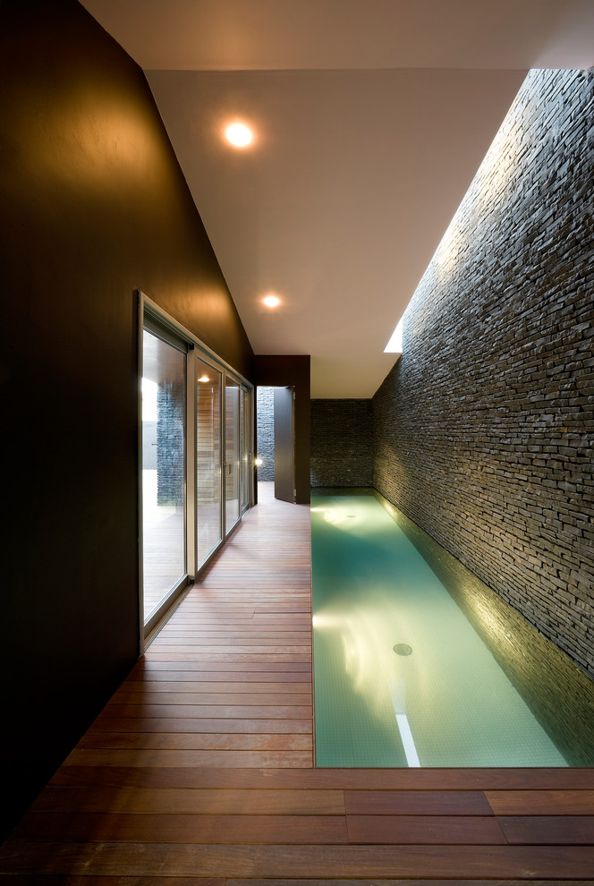 Cette image montre une petite piscine intérieure design rectangle avec une terrasse en bois.