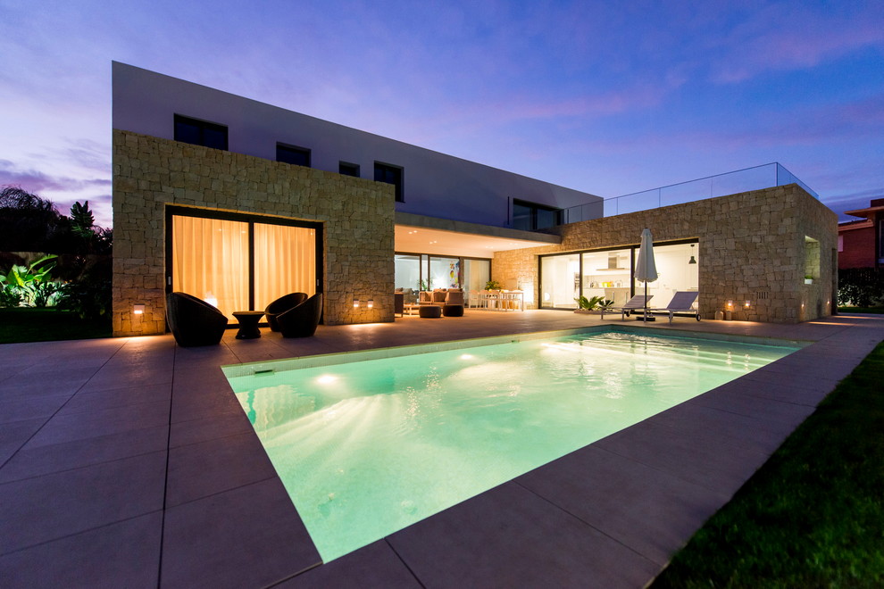 Foto de casa de la piscina y piscina alargada actual de tamaño medio rectangular en patio lateral con suelo de baldosas