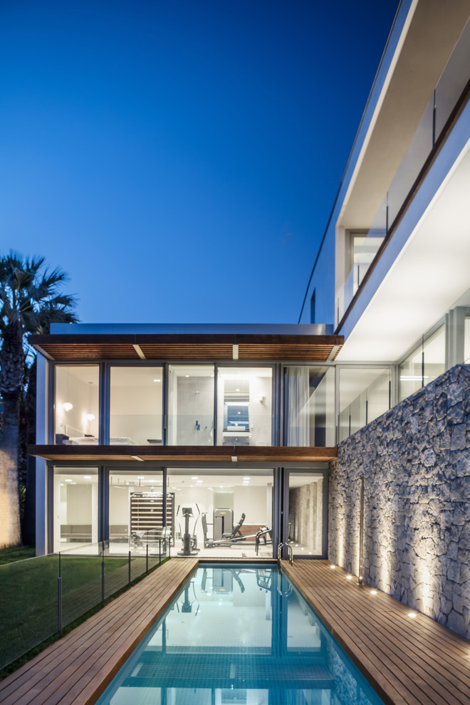 Foto di una piscina monocorsia moderna rettangolare dietro casa con pedane