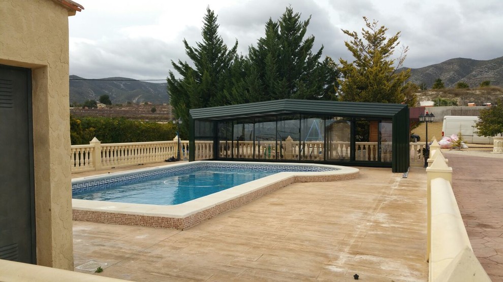 Ejemplo de casa de la piscina y piscina elevada mediterránea grande rectangular en patio delantero con adoquines de ladrillo
