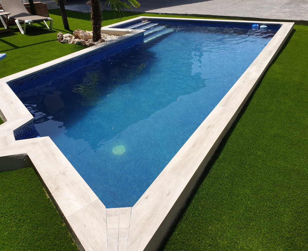Diseño de piscina mediterránea grande rectangular en patio trasero