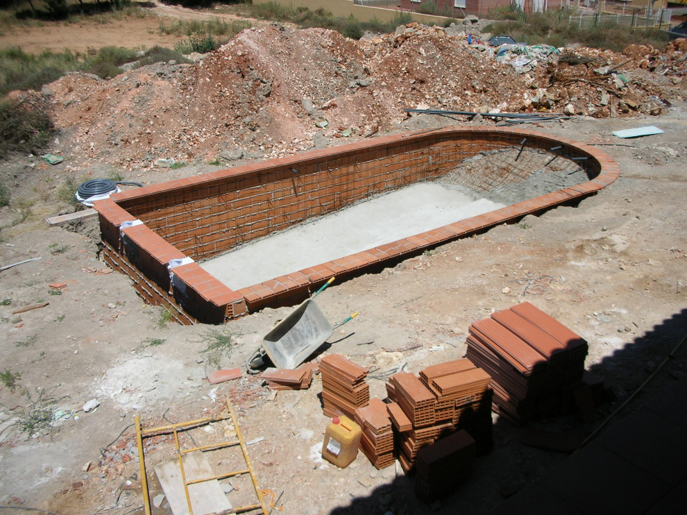 Imagen de piscina alargada de estilo de casa de campo grande a medida en patio trasero con privacidad y suelo de baldosas