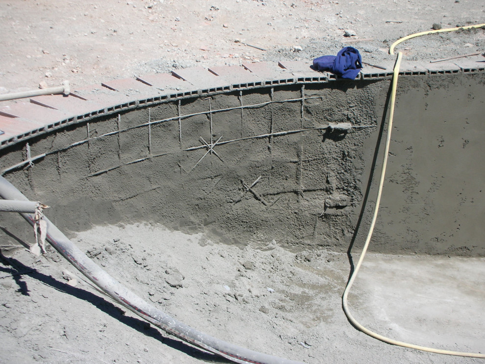 Ejemplo de piscina alargada campestre grande a medida en patio trasero con privacidad y suelo de baldosas