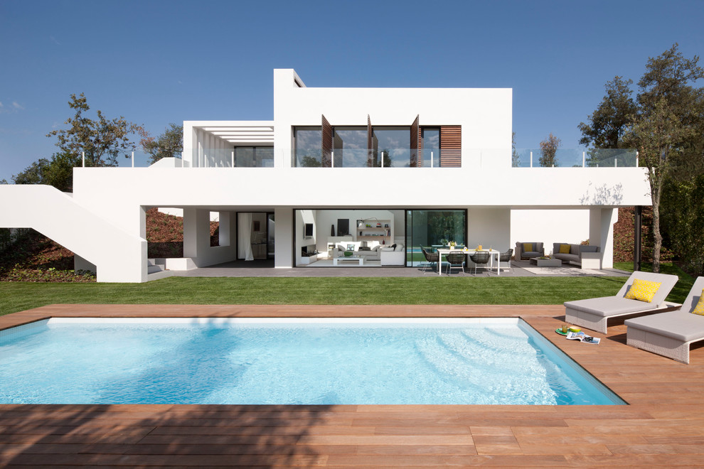 Ejemplo de casa de la piscina y piscina alargada actual de tamaño medio rectangular en patio trasero con entablado