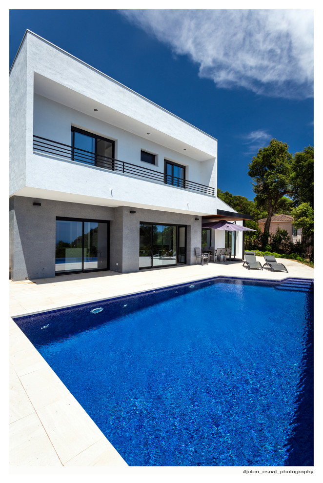 Großer, Gefliester Moderner Infinity-Pool hinter dem Haus in rechteckiger Form mit Pool-Gartenbau in Sonstige