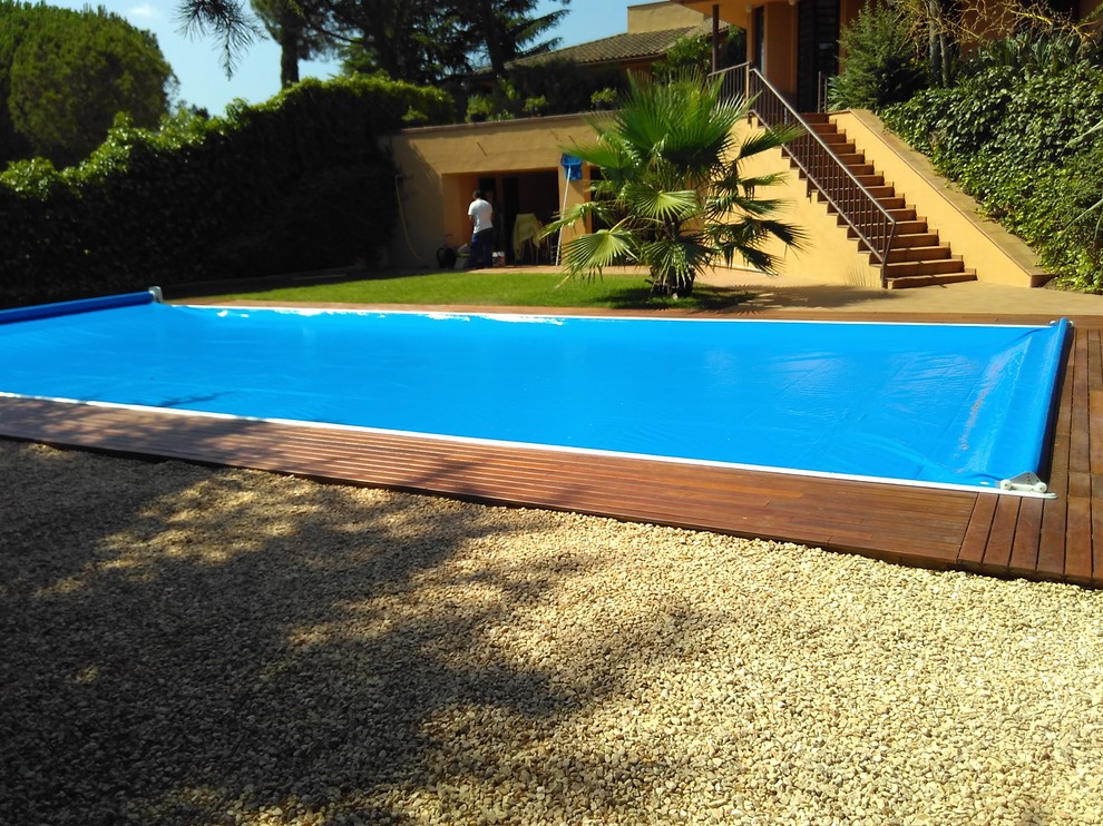 Ejemplo de casa de la piscina y piscina alargada actual grande rectangular con entablado