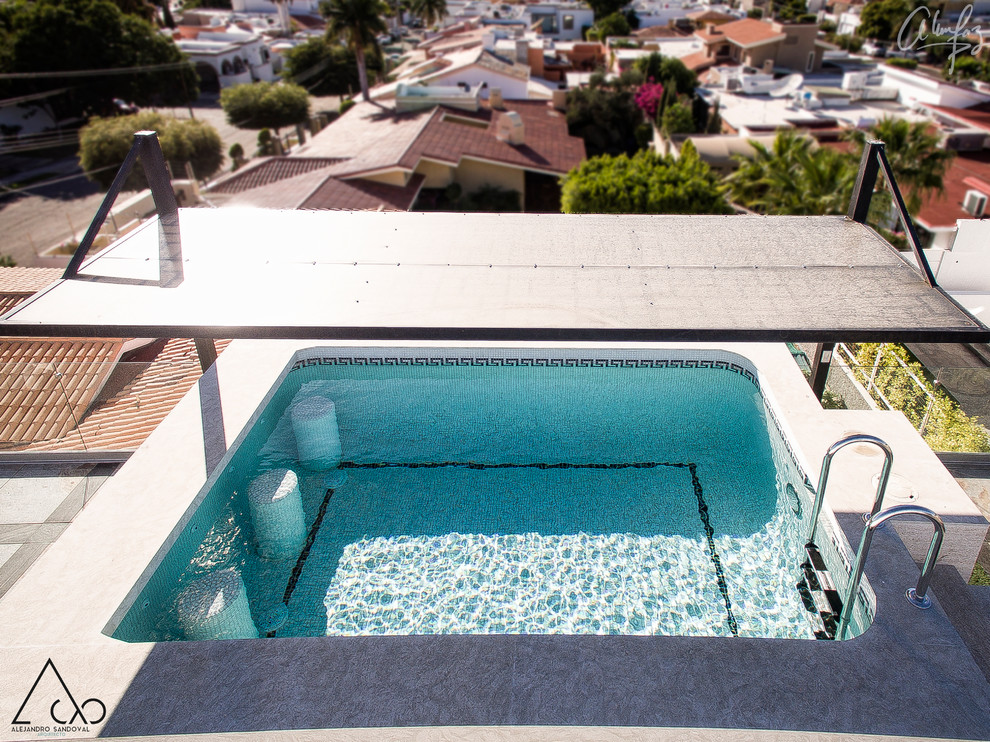 Esempio di una piscina fuori terra tropicale rettangolare di medie dimensioni e sul tetto con graniglia di granito