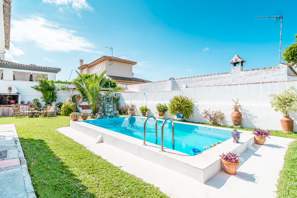 Imagen de piscina alargada mediterránea rectangular en patio trasero con losas de hormigón