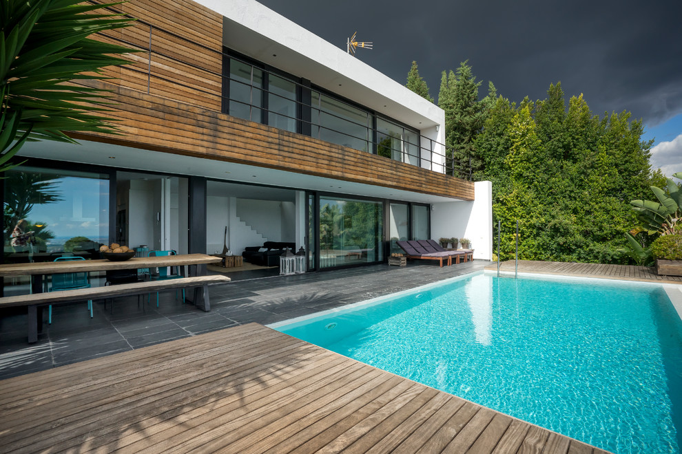 Imagen de piscina infinita contemporánea rectangular en patio trasero con entablado