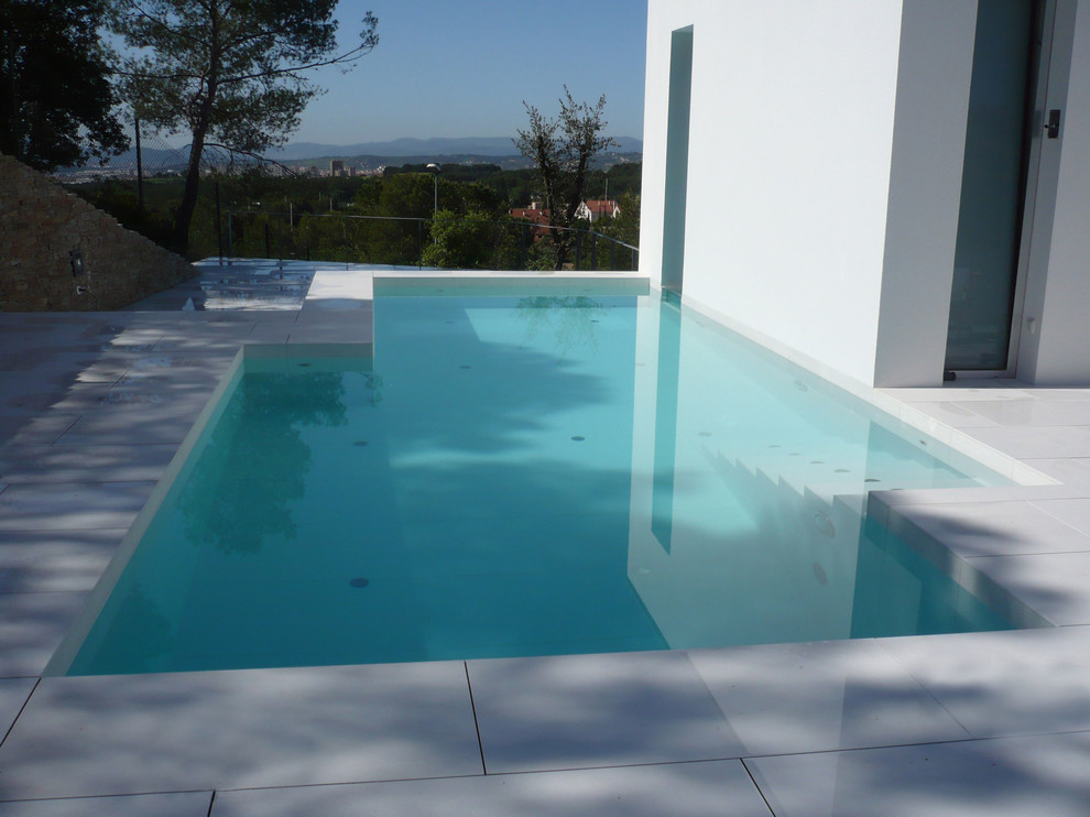 Photo of a medium sized modern side custom shaped above ground swimming pool in Barcelona with a pool house and tiled flooring.