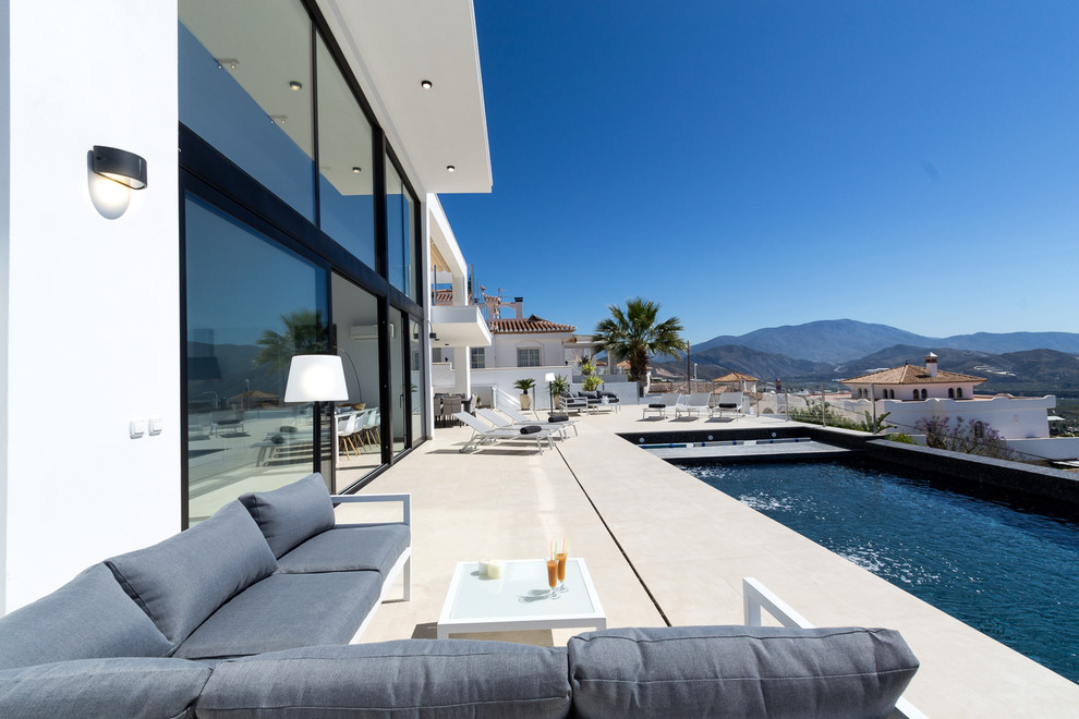 Foto de piscina infinita contemporánea grande rectangular en patio trasero con granito descompuesto
