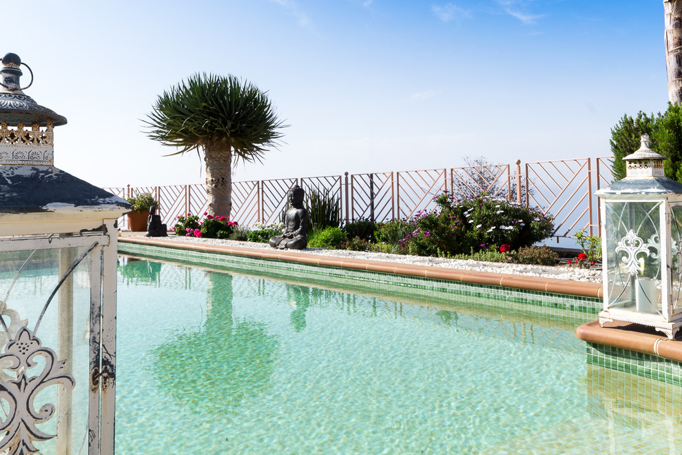 Imagen de piscina alargada tropical grande rectangular en patio trasero con adoquines de piedra natural