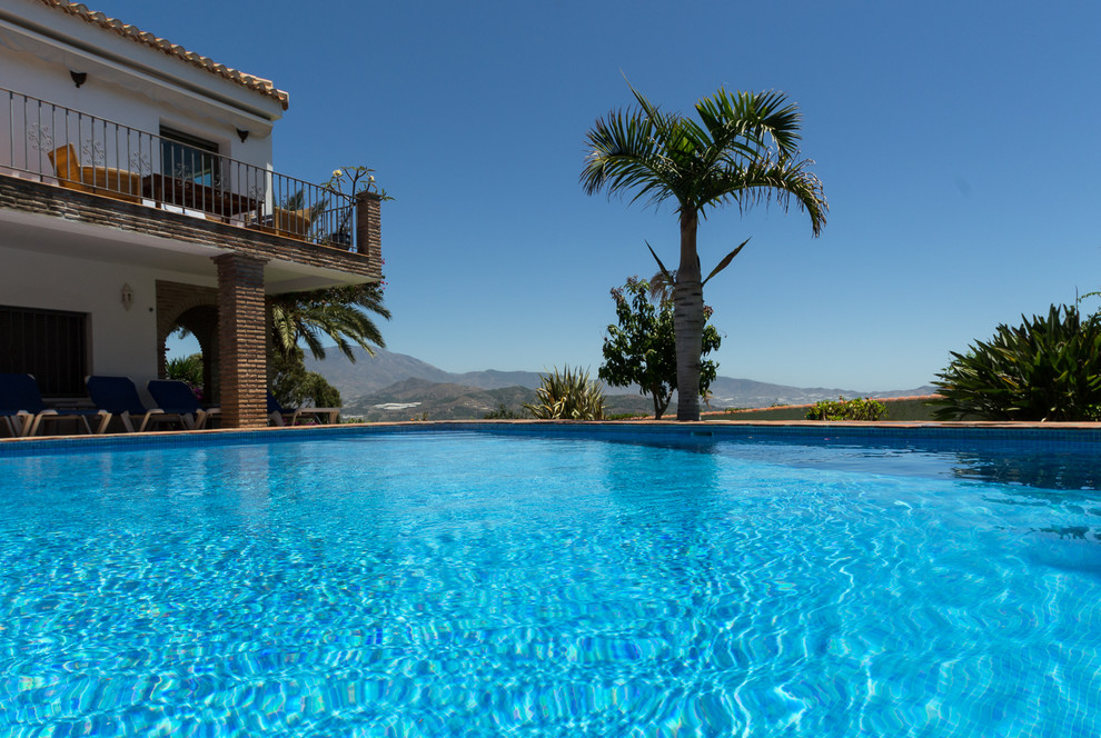 Foto de piscina alargada mediterránea grande rectangular en patio trasero con adoquines de ladrillo