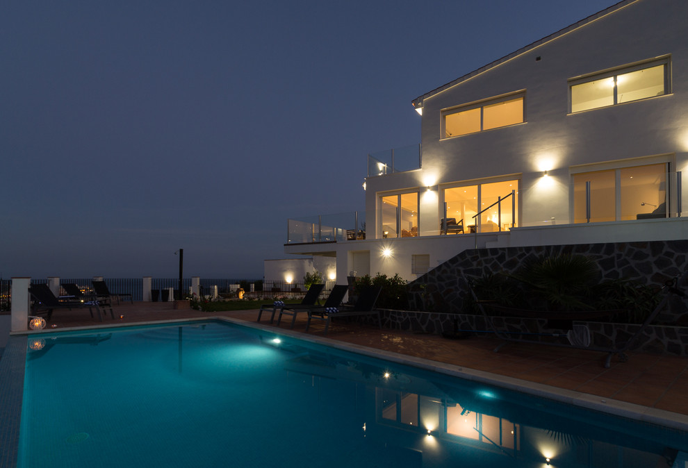 Ejemplo de piscinas y jacuzzis alargados mediterráneos extra grandes rectangulares en patio lateral con adoquines de ladrillo